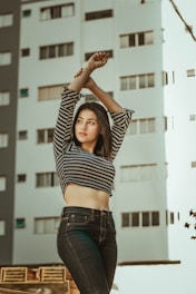woman wearing gray and black striped long-sleeve crop top holding her wrist