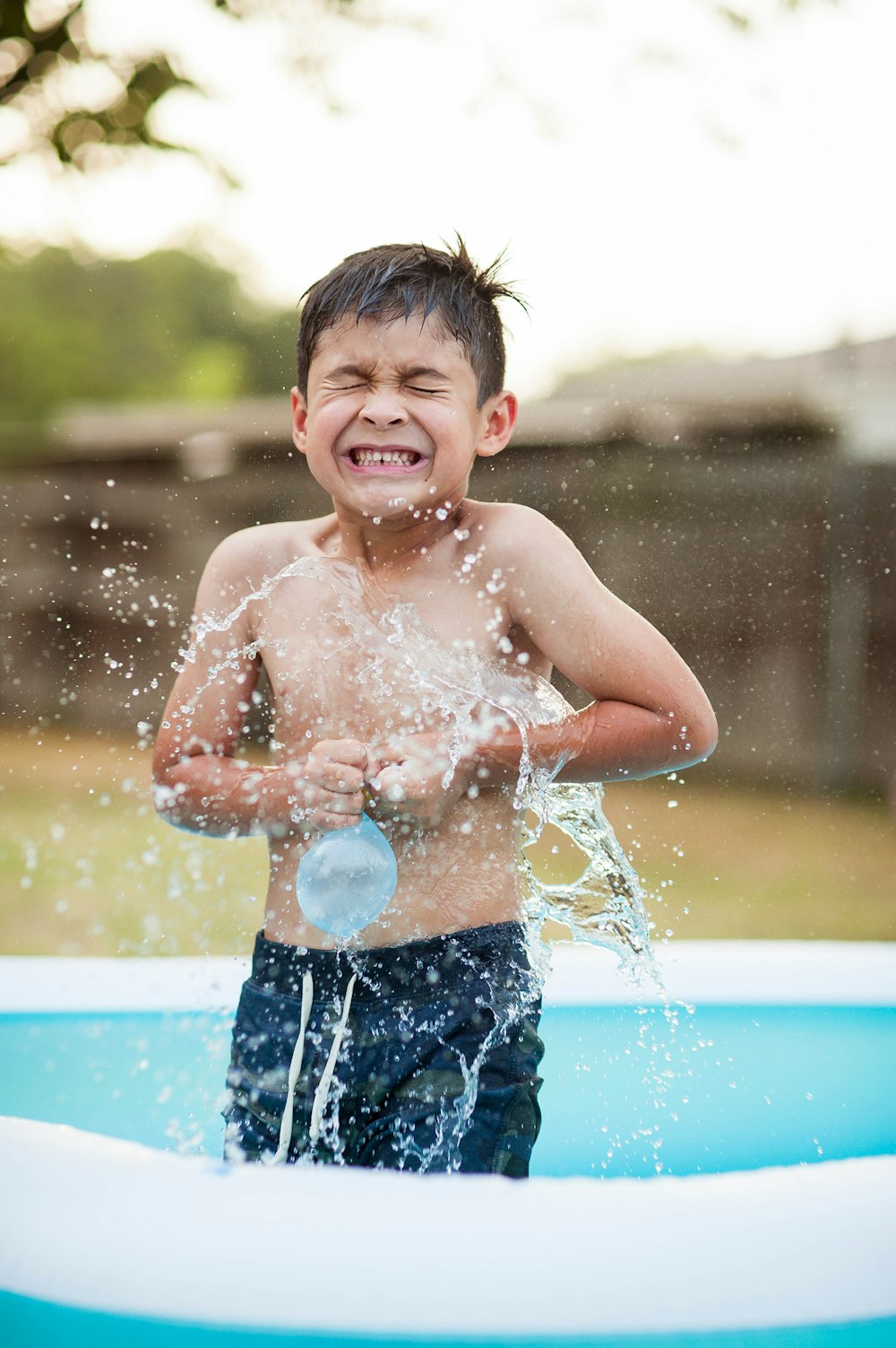 niño jugando globo de plástico dentro de la piscina inflable