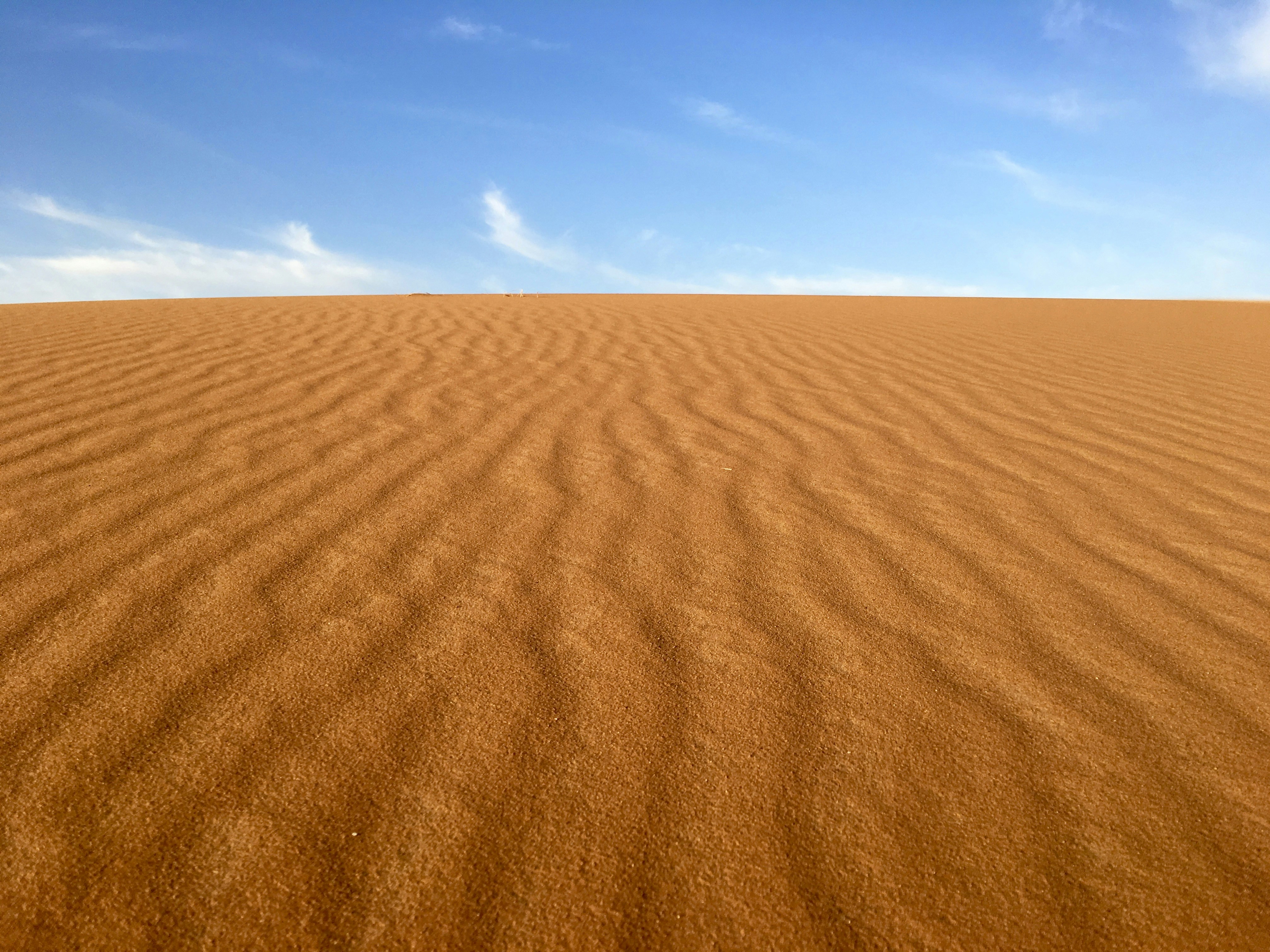 Brown sand under blue and white sky