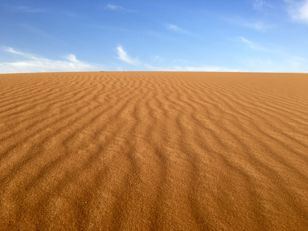 brown sand under blue and white sky
