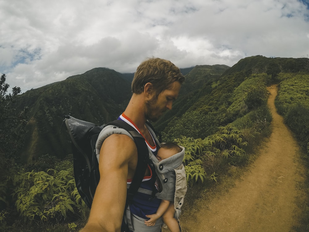 man carrying baby in carrier