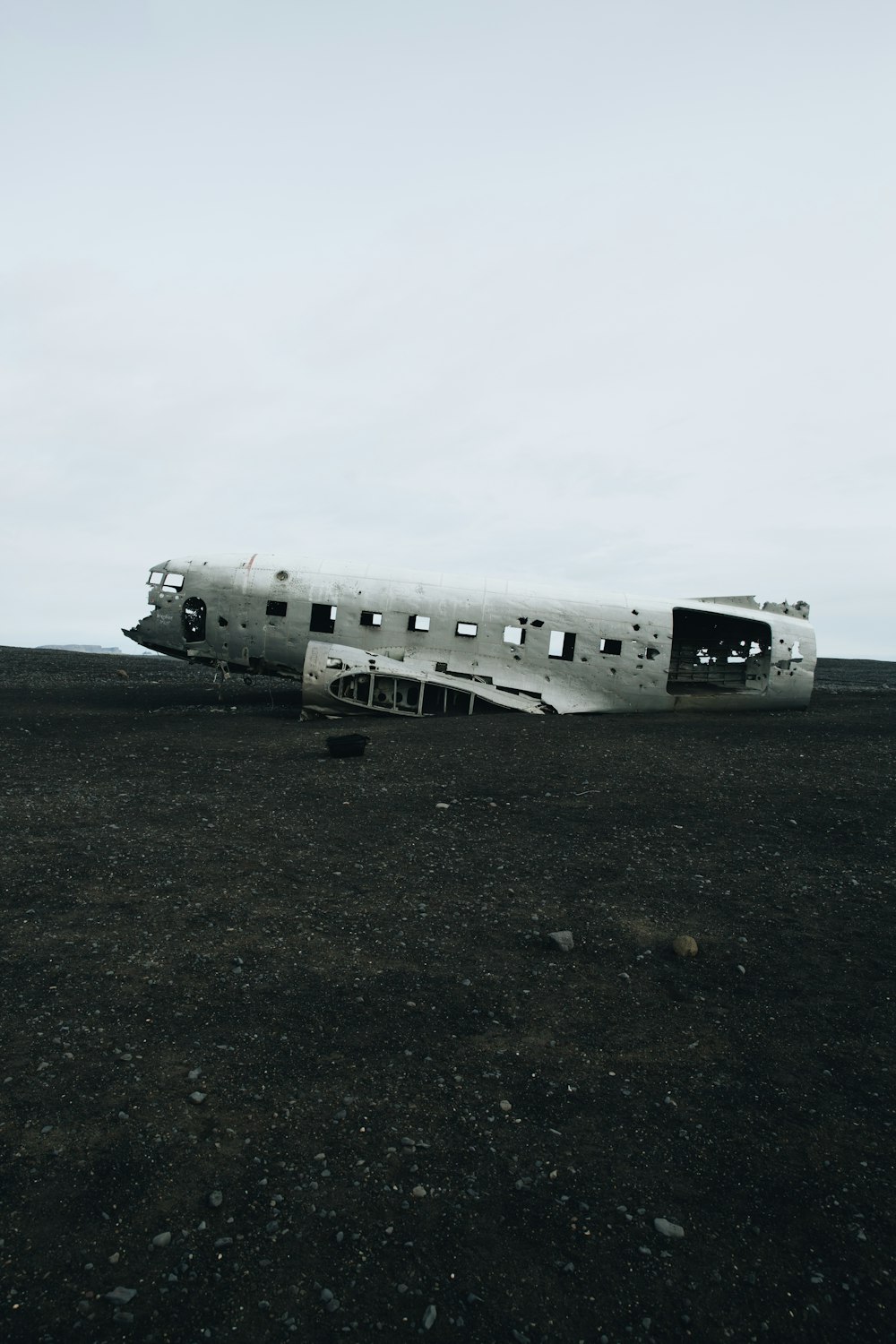 Zerstörtes weißes Flugzeug auf ebenem Gelände bei Tag