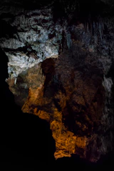 A cozy, dimly lit cave interior with colorful abstract art pieces illuminating the dark walls.