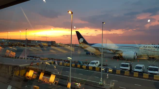 A sleek bus parked outside Kuala Lumpur International Airport during sunset.