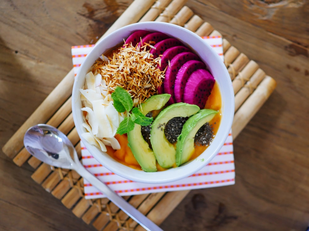 sliced fruits on bowl beside gray spoon