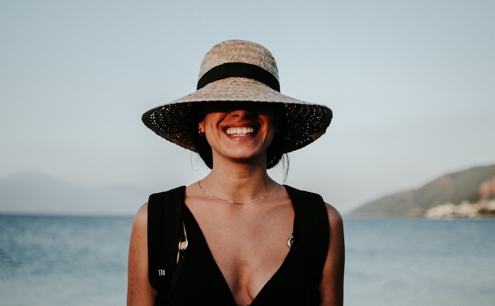 mulher usando chapéu de sol enquanto sorri
