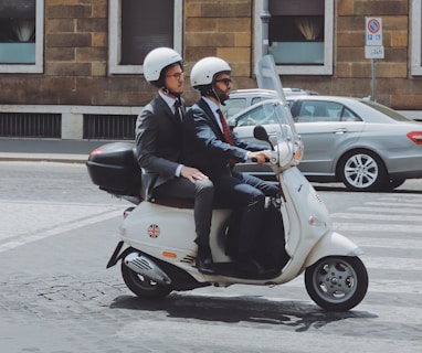 two men riding on motor scooter