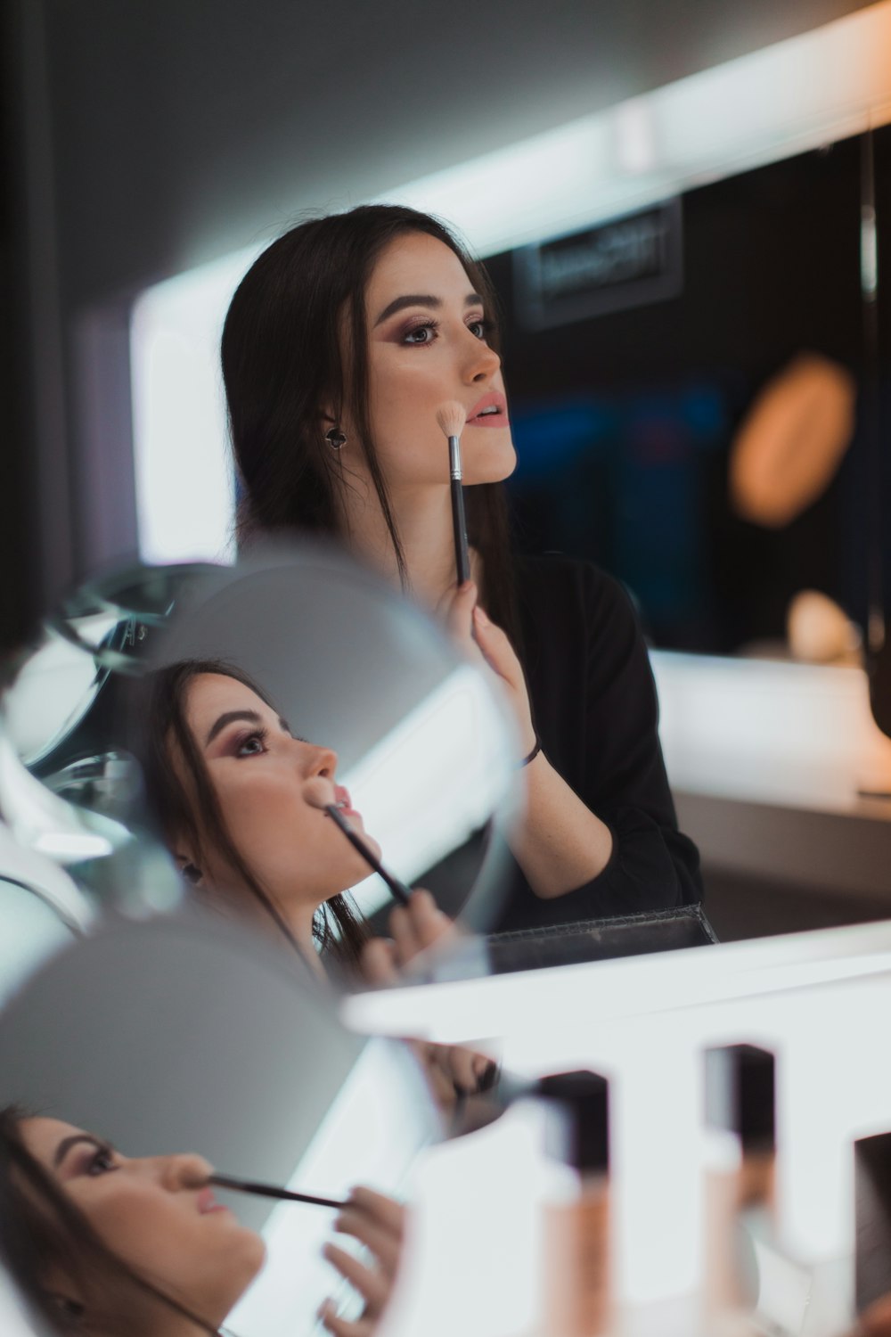 shallow focus photography of woman doing makeup