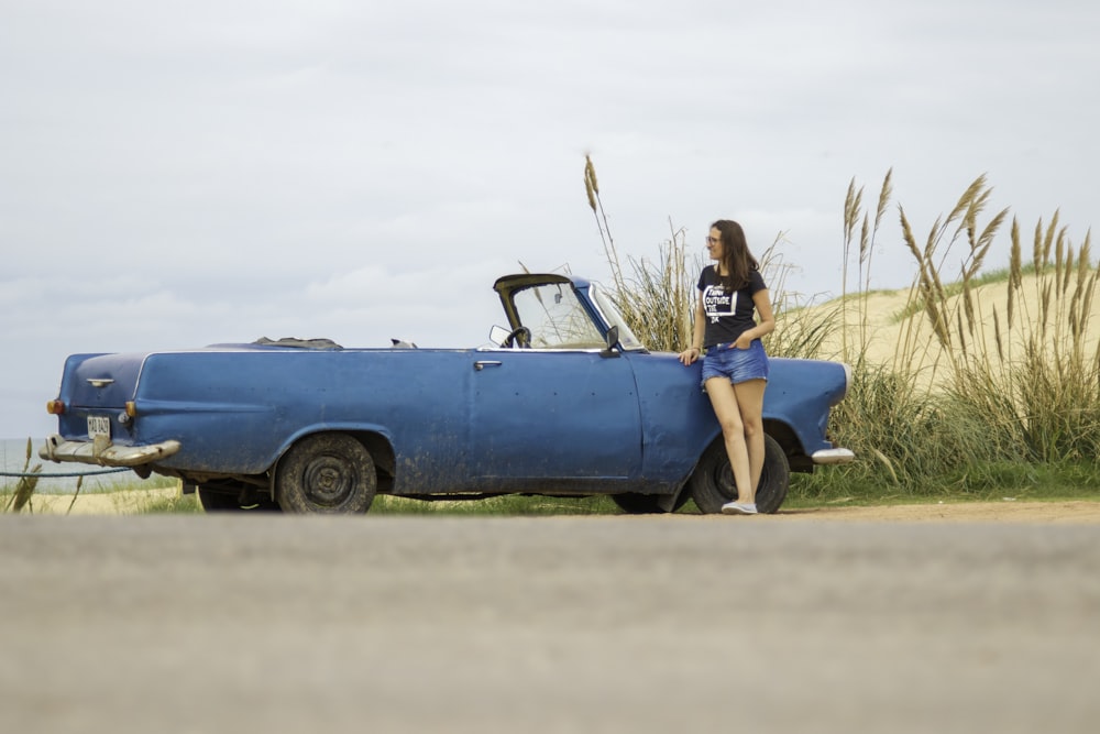 woman leaning on blue convertible coupe