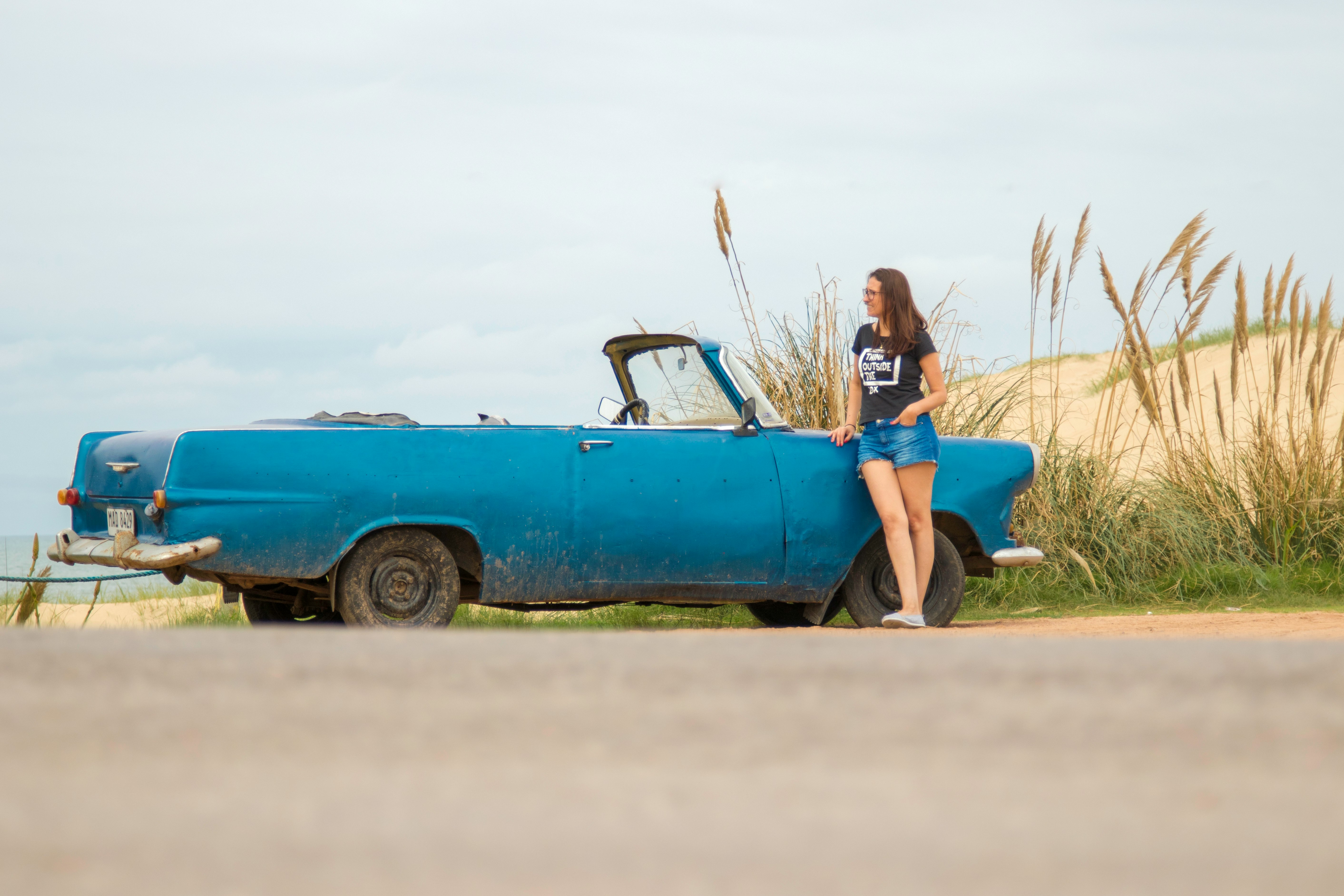 woman leaning on blue convertible coupe