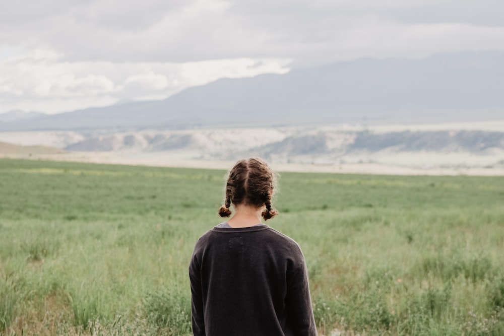 femme debout devant un champ d’herbe verte pendant la journée