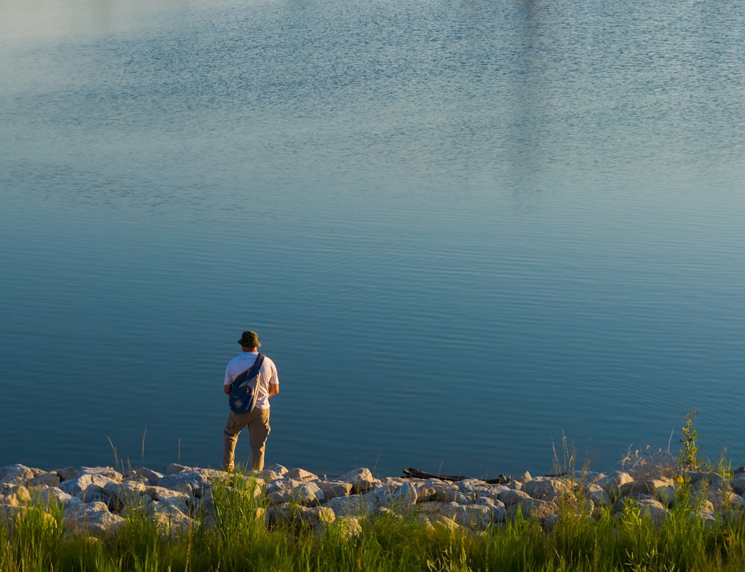 rule of thirds photography of person standing beside body of water