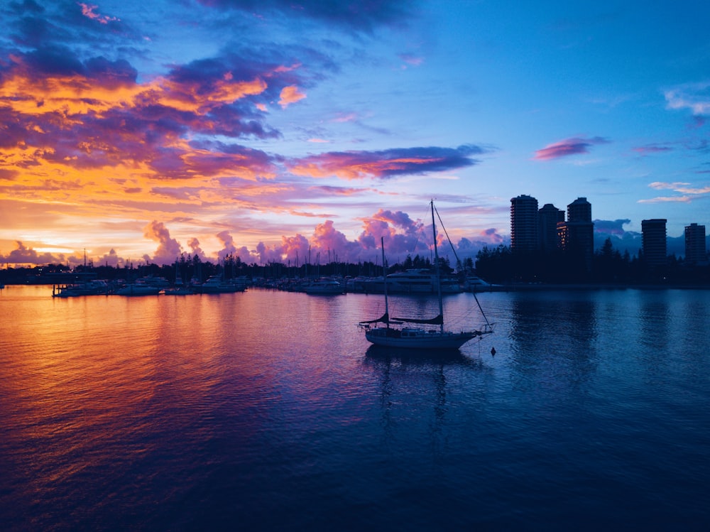 silhouette of boat on body of water near high rise buildings during golden hour