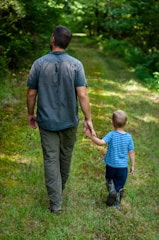 man in gray polo shirt and gray pants holding child in blue shirt