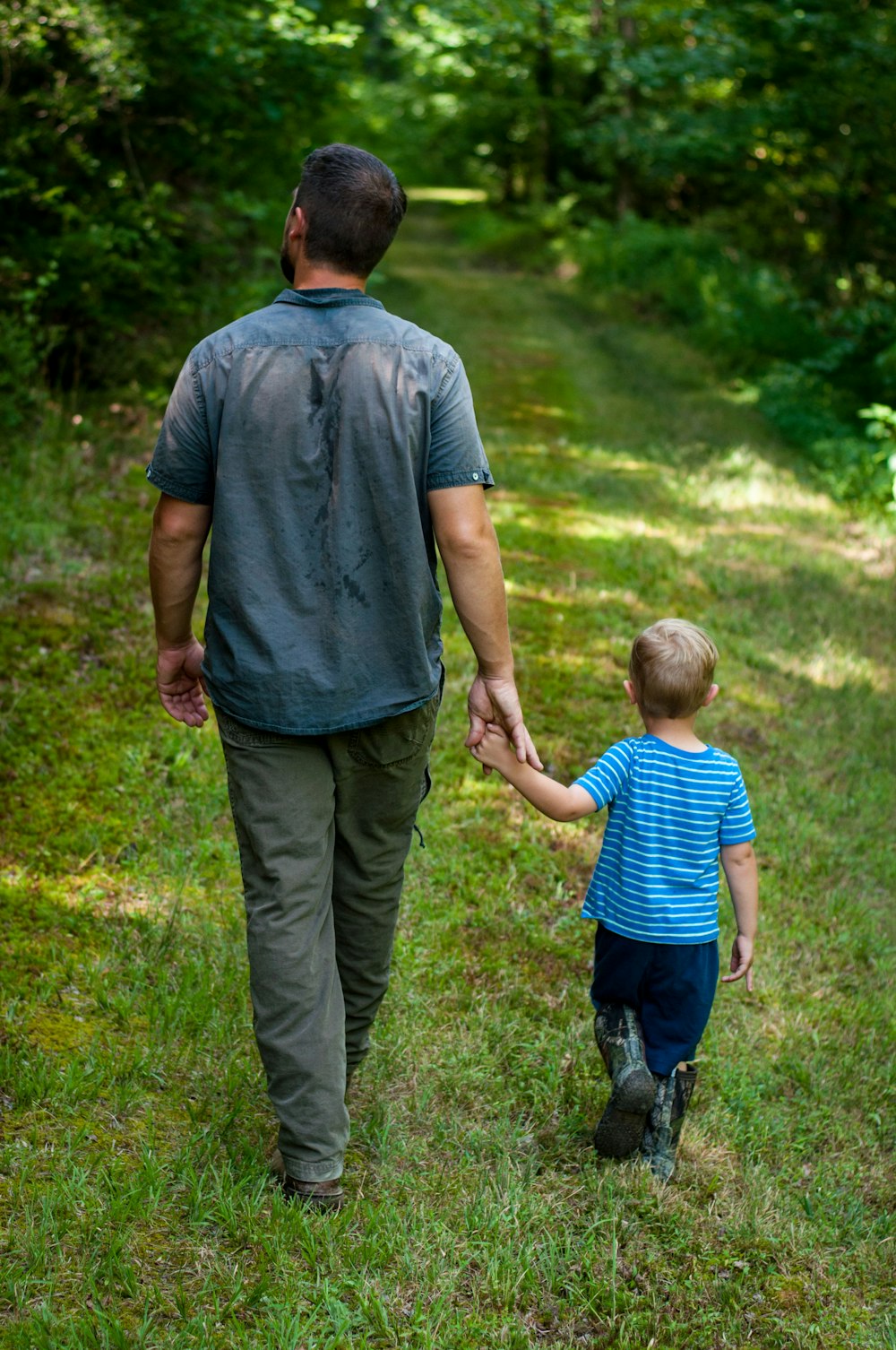 uomo in polo grigia e pantaloni grigi che tengono bambino in camicia blu