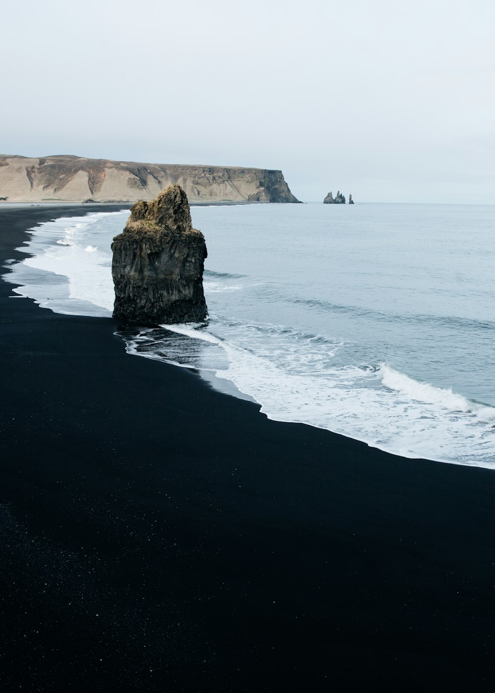 brown monolith rock on seashore