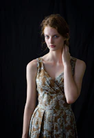A model wearing a flowy dress with delicate bracelets and layered necklaces against a soft sunlit backdrop.