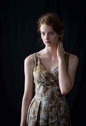A model wearing a flowy dress with delicate bracelets and layered necklaces against a soft sunlit backdrop.