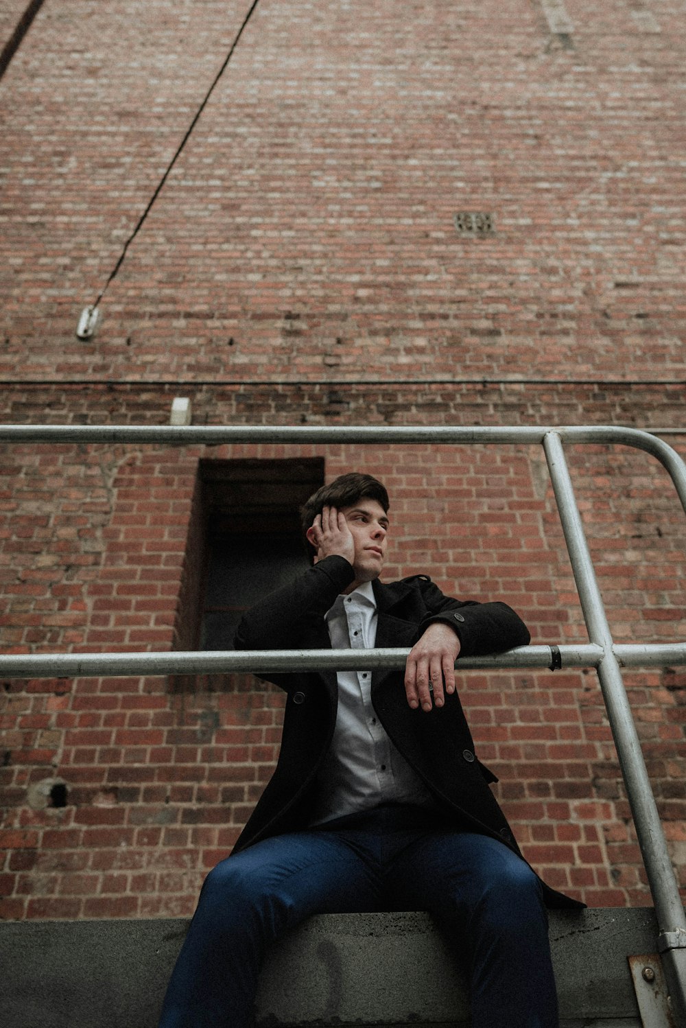 Man Sitting On Gray Floor With His Right Hand On His Face Photo