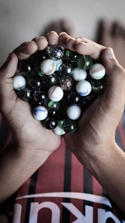 Hand holding a spiral of multicolored pipe cleaners against a wooden table
