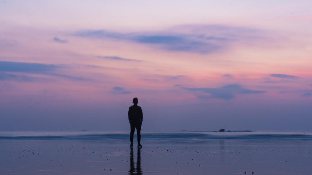 silhouette of man standing on seashore