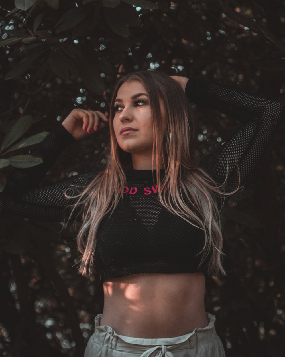 women wearing black mesh crop top standing behind tree