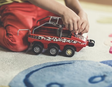 person playing red and black vehicle toy