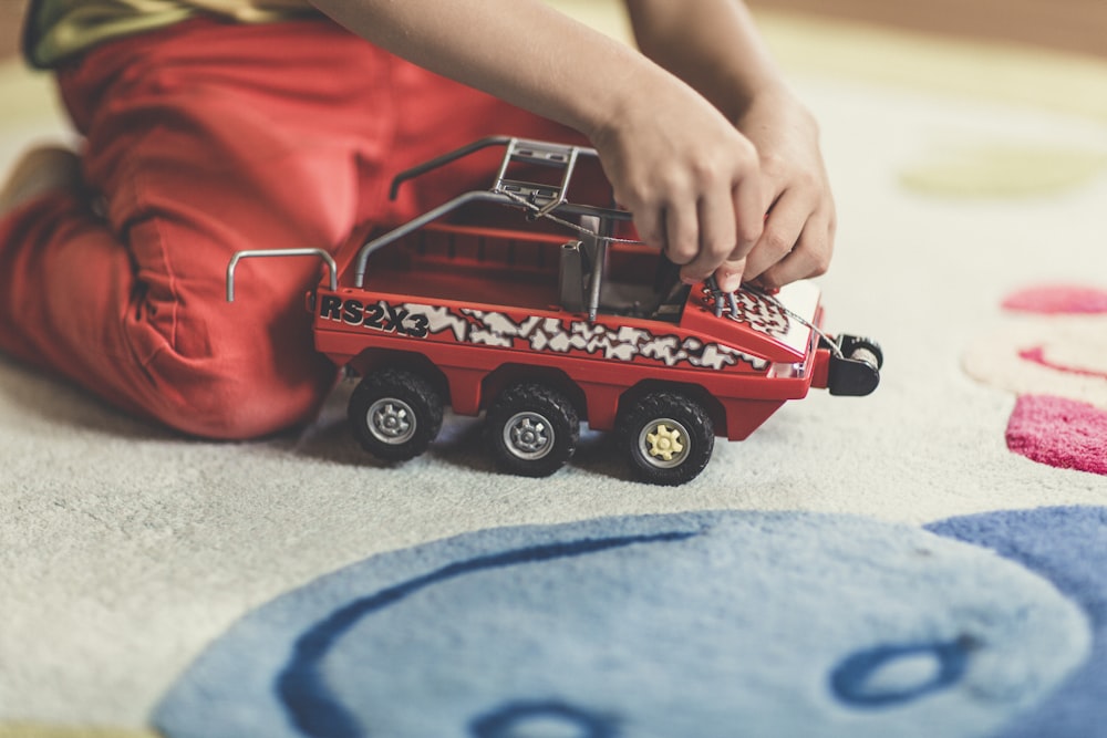 person playing red and black vehicle toy
