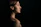Profile of a professional woman with short hair, illuminated softly against a deep charcoal backdrop with gold accents.