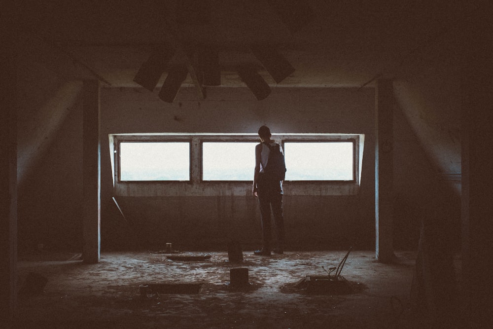 man standing in front of windows while carrying backpack