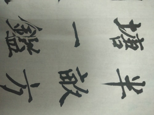 Several Chinese characters written in black ink on a white paper. The characters are bold and artistic, showcasing traditional calligraphy style.
