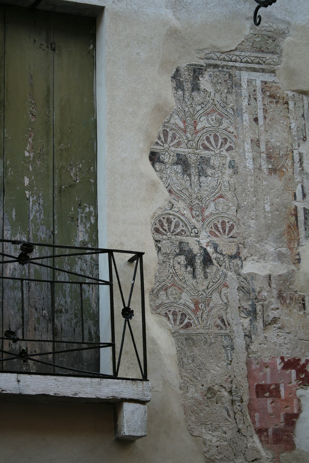 a balcony with a wrought iron railing next to a painted wall