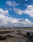 Ground service equipment lined up at a busy airport runway.