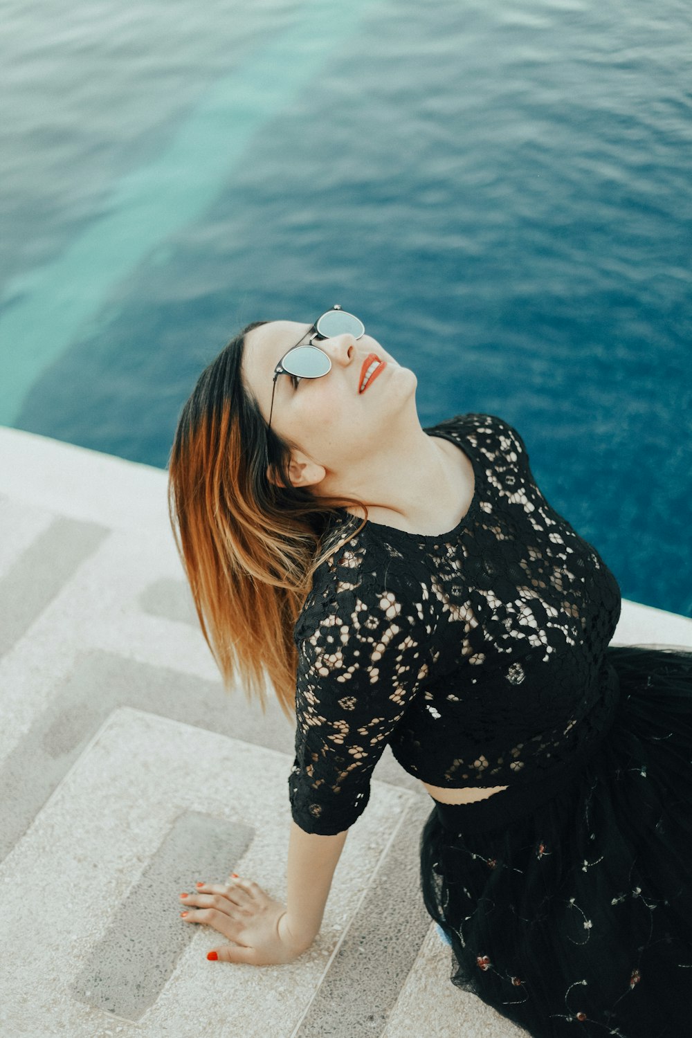 smiling woman looking upwards near sea