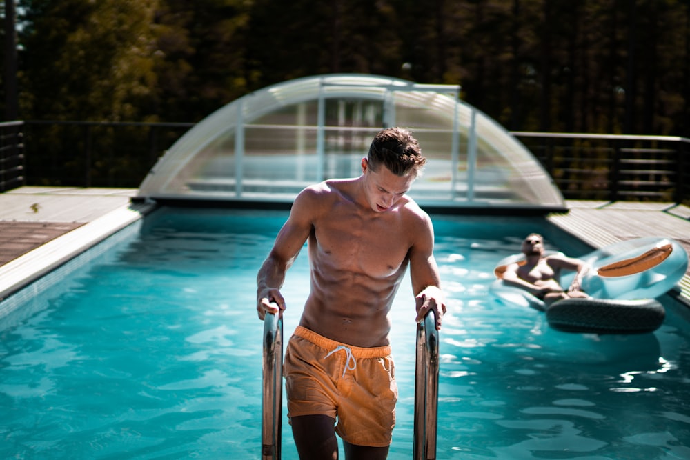 man holding grey steel swimming pool ladder