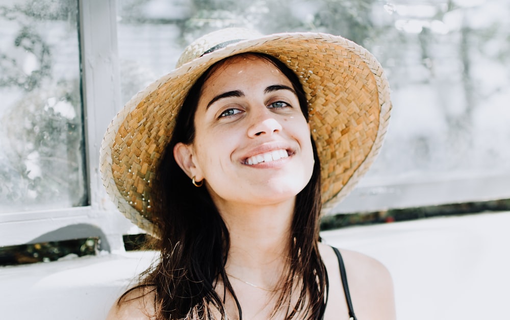 femme portant un haut à bretelles noir avec un chapeau de soleil