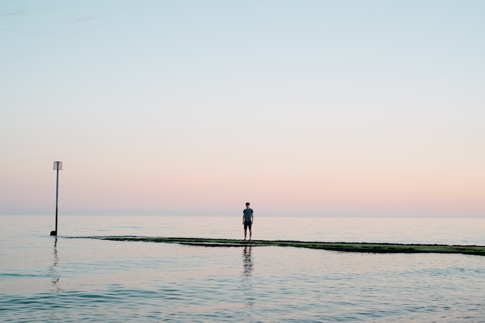 homme debout sur le quai entre le plan d’eau