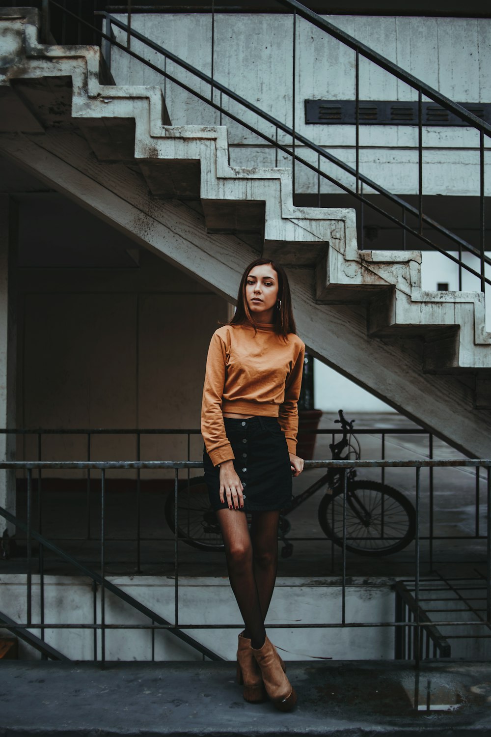 photography of woman leaning on guard rail beside stair at daytime