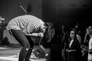 grayscale photography of people watching a man performing on stage
