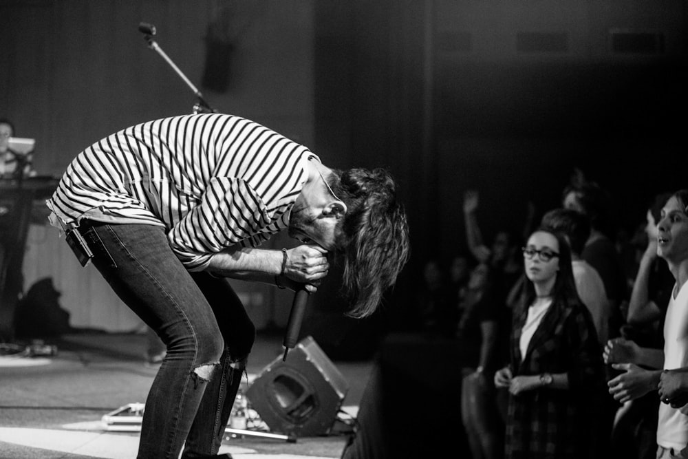 grayscale photography of people watching a man performing on stage