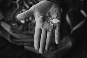 A close-up of an outstretched hand holding various small metallic and bead-like objects. The background is softly blurred, drawing focus to the detailed textures of the hand and the items.