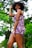 A joyful woman wearing a vibrant floral summer dress outdoors.