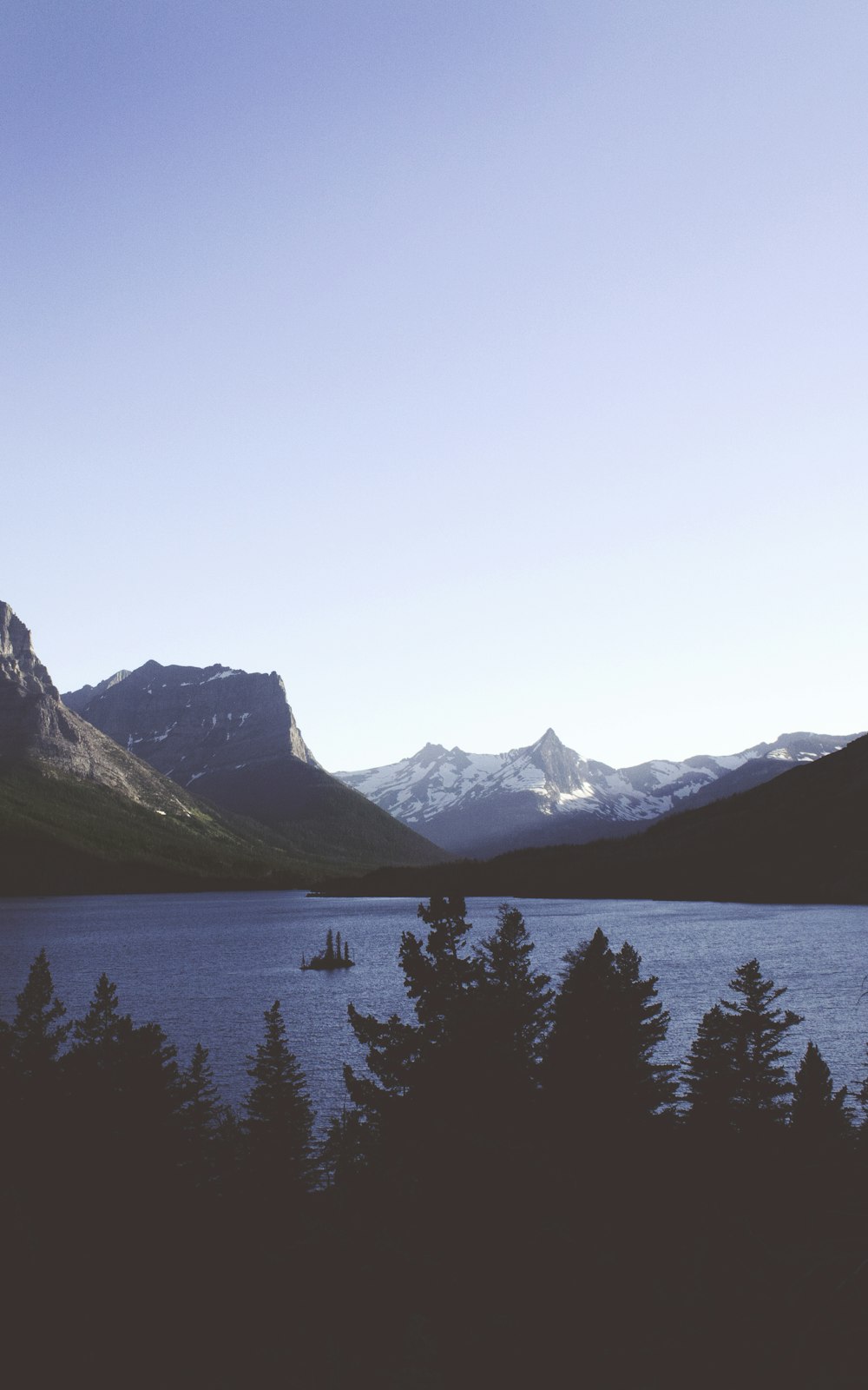 lake surrounded with snow-capped mountains at daytime