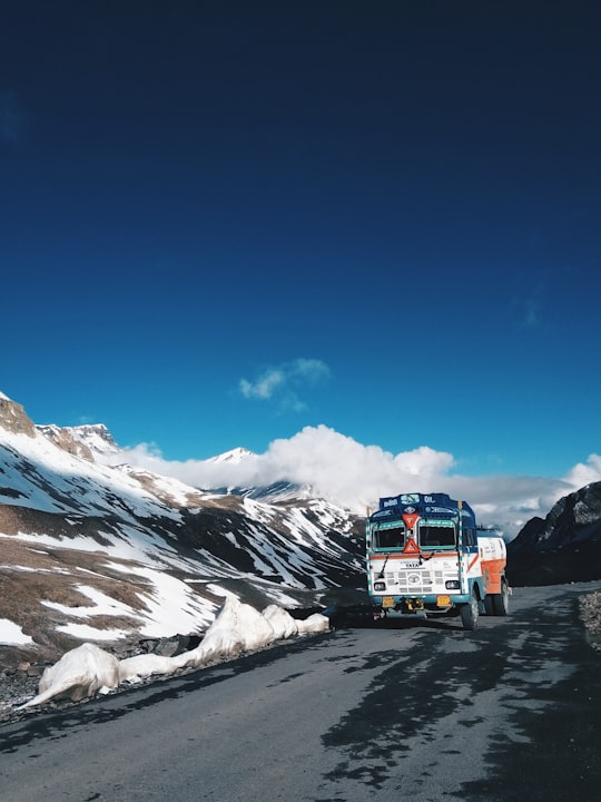 white truck running on gray pave road near mountain in Baralacha La Pass India