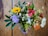 A colorful seasonal bouquet featuring lilies, daisies, and wildflowers on a wooden table.