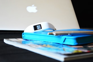 Close-up of a clock and a stack of work documents on a desk.