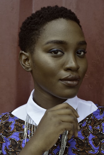 Headshot photography in Toronto, women holding her collar standing near wall