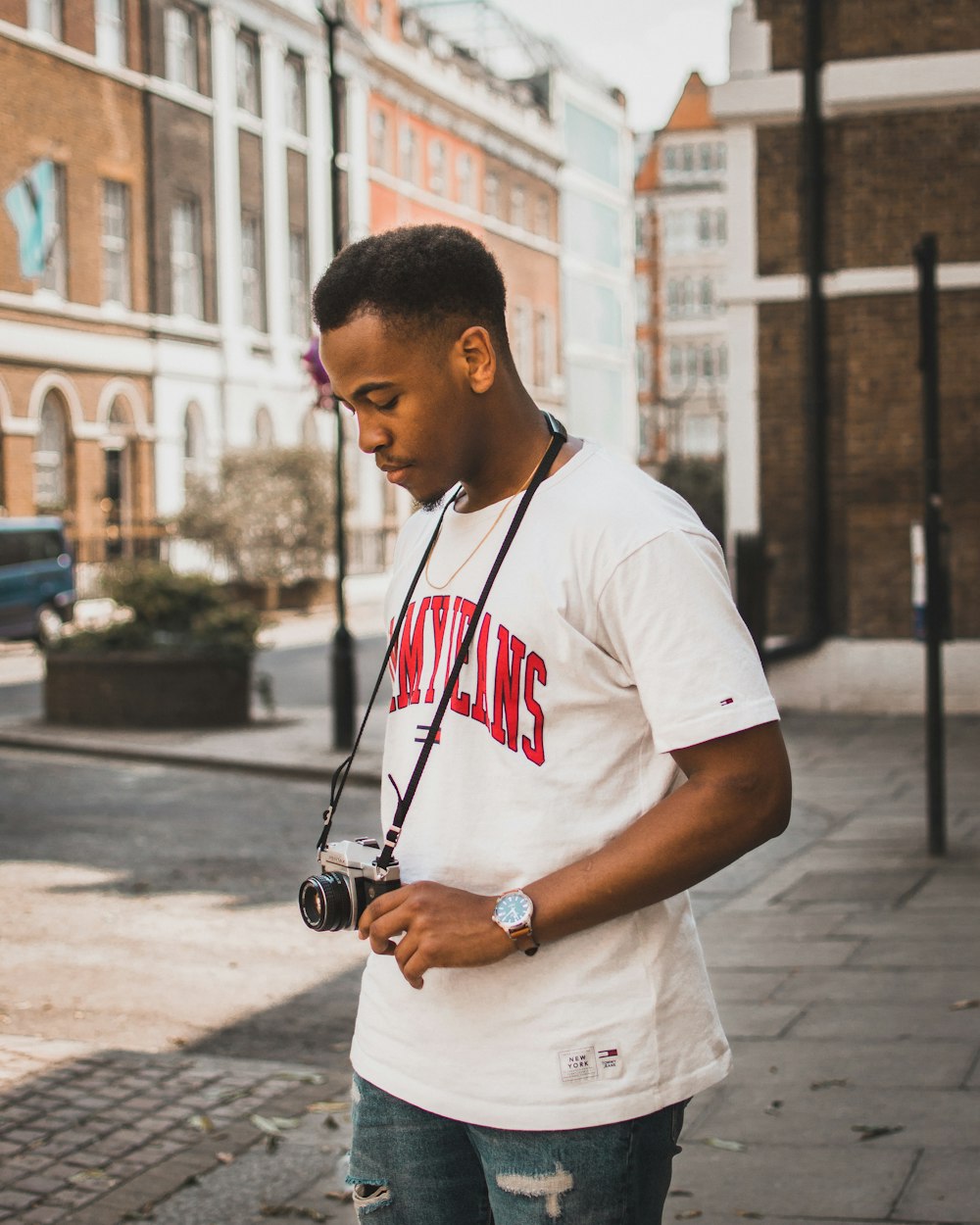 man standing white holding camera near brown concrete building