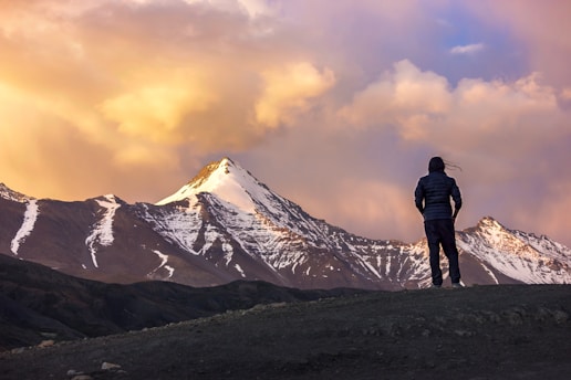 person at the top of mountain facing another mountain