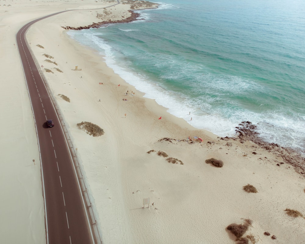 Photo aérienne d’un véhicule noir se déplaçant près du rivage pendant la journée